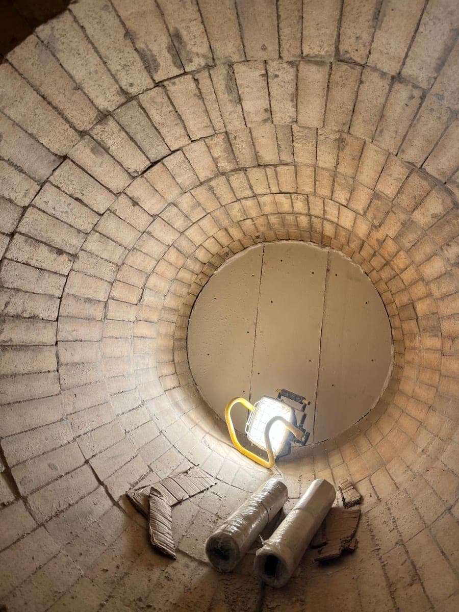Muratura circolare nel tino vista dal basso, con lampada da lavoro