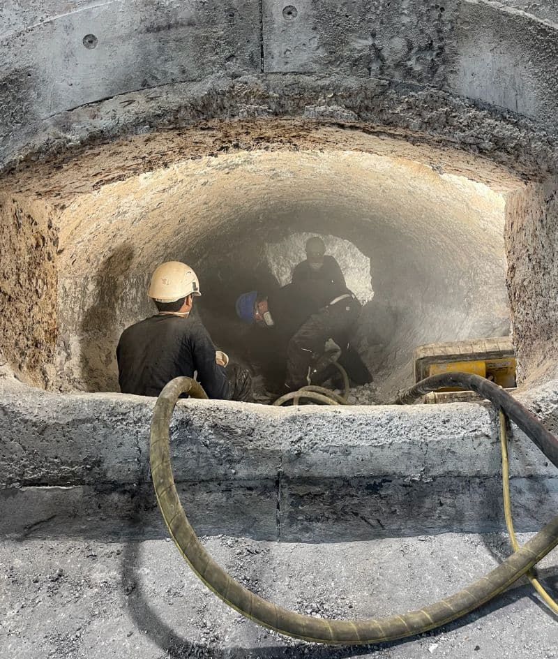Facharbeiter führt eine Pflegespritzung mit Shotcrete-Verfahren an einem Industrieofen durch