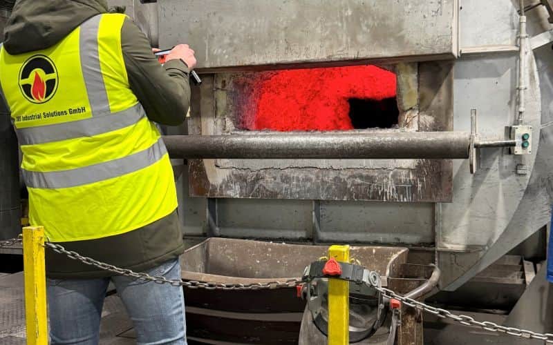 Close-up of a worn refractory lining in an aluminium furnace with visible cracks and slag deposits